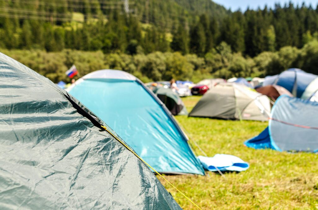 pexels-photo-1309584-1309584 Vibrant camping tents set up in a lush forest landscape under a sunny sky.